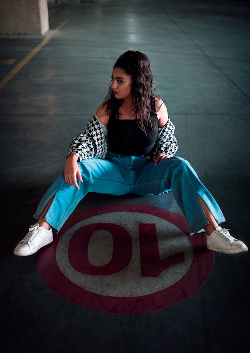 Photo of a Woman in Denim Jeans Sitting on the Floor