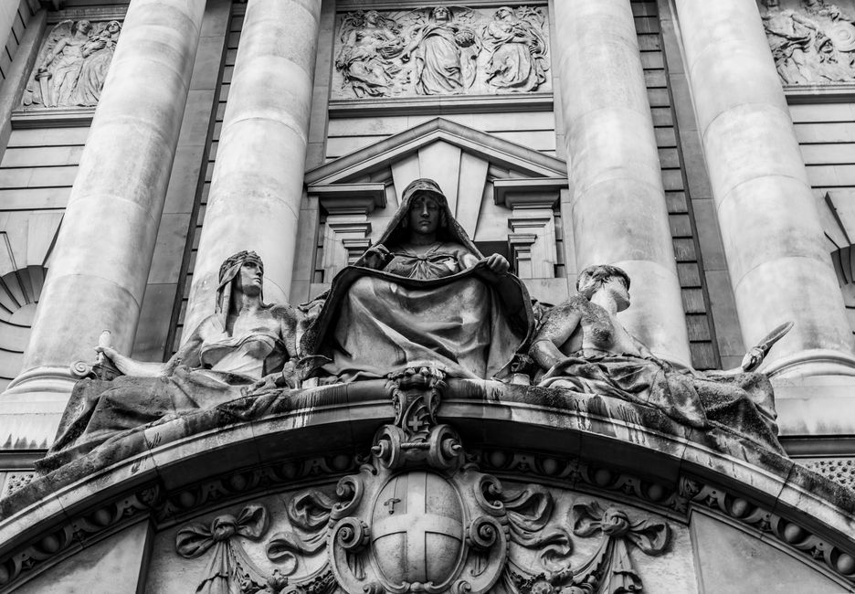 Black and white photo of ornate sculptures on a historic building in London. Urban and artistic shot.