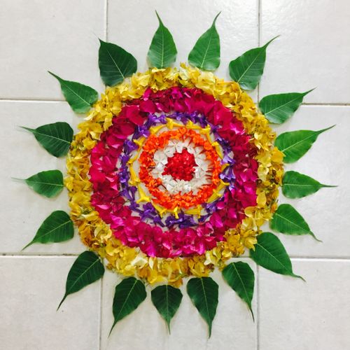 Free A vibrant floral mandala made of colorful petals and green leaves arranged on a tile floor. Stock Photo