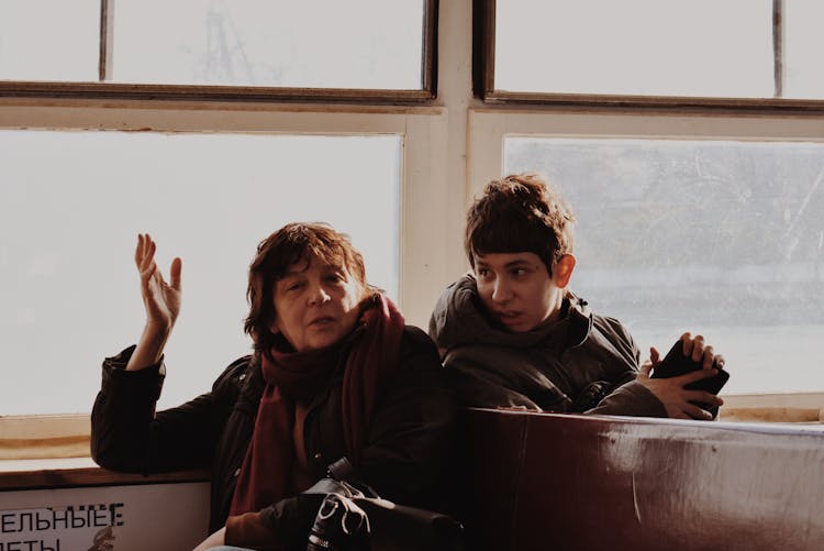 People Sitting In Train Near Window Talking