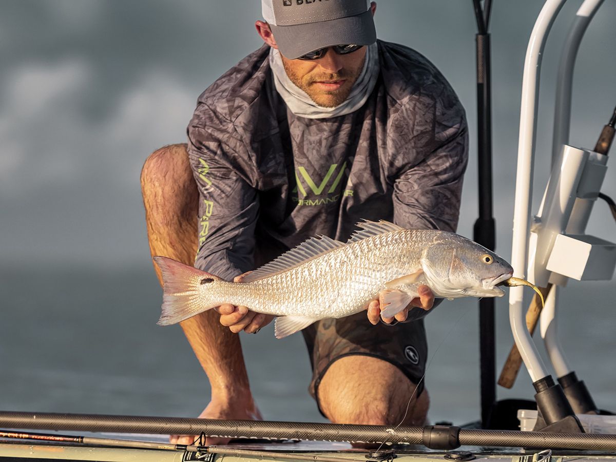 An angler holding a freshly caught fish beside the water