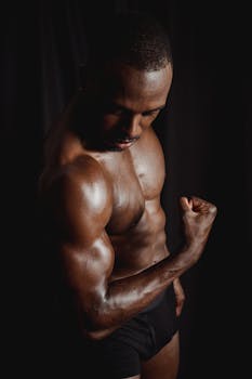 African American bodybuilder flexing muscles, showcasing strength and fitness in a dark studio.