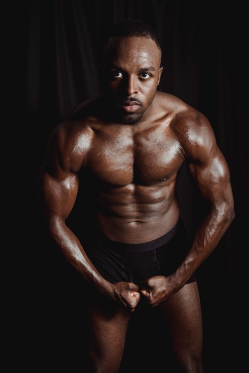 Free Portrait of a muscular man flexing in underwear, showcasing strength and fitness in a studio setting. Stock Photo