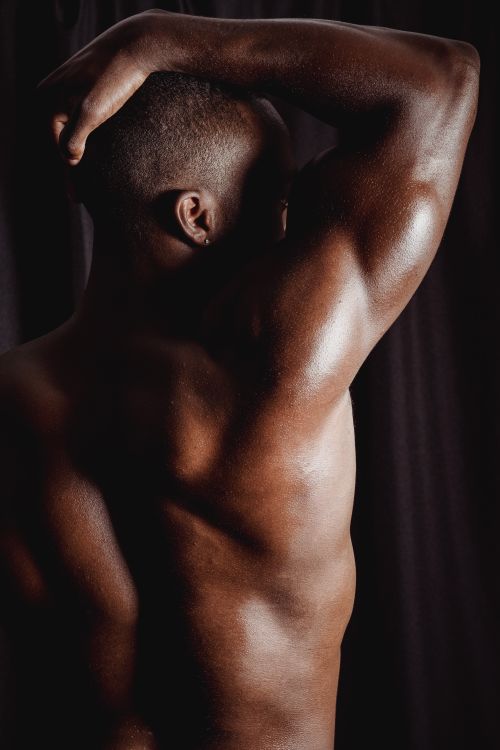 Free A shirtless muscular black man flexing his arm, showcasing strength and fitness. Stock Photo