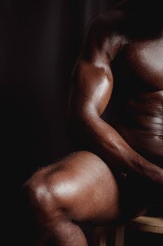 A close-up of a muscular man's torso and arm, emphasizing strength and physique.