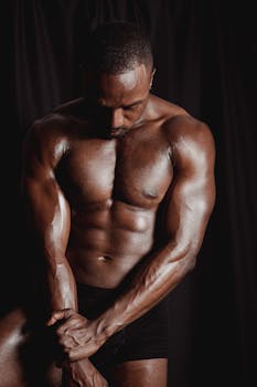 Portrait of a muscular African American male in a studio, showcasing strength and physique.