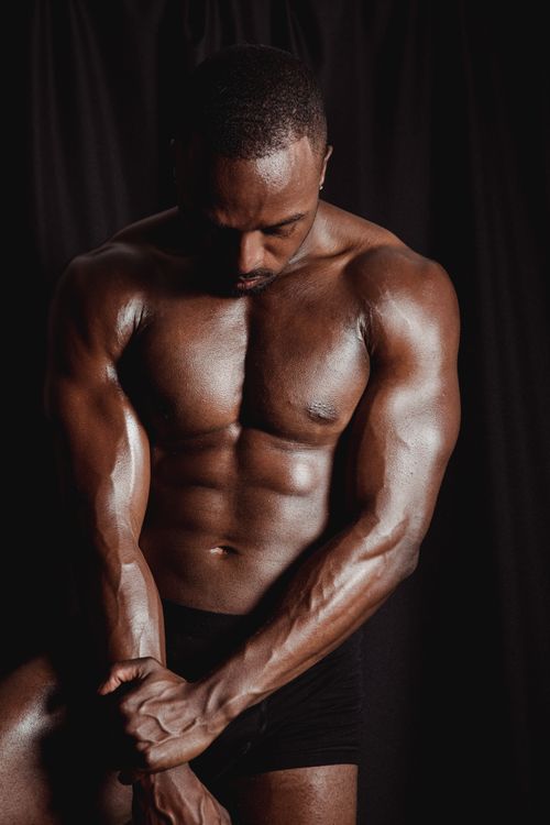 Free Portrait of a muscular African American male in a studio, showcasing strength and physique. Stock Photo