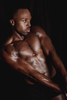 Shirtless muscular African American man posing in studio with dramatic lighting.