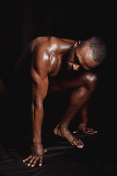 A strong, shirtless man showcasing athletic physique against a dark background.