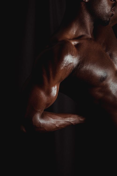 Free Close-up of a muscular man's arm flexing against a dark background. Stock Photo