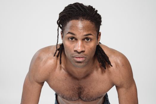 Shirtless man in athletic pose on white studio background, highlighting strength and fitness.