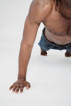 Close-up of a shirtless man performing a push-up exercise on a white studio background.