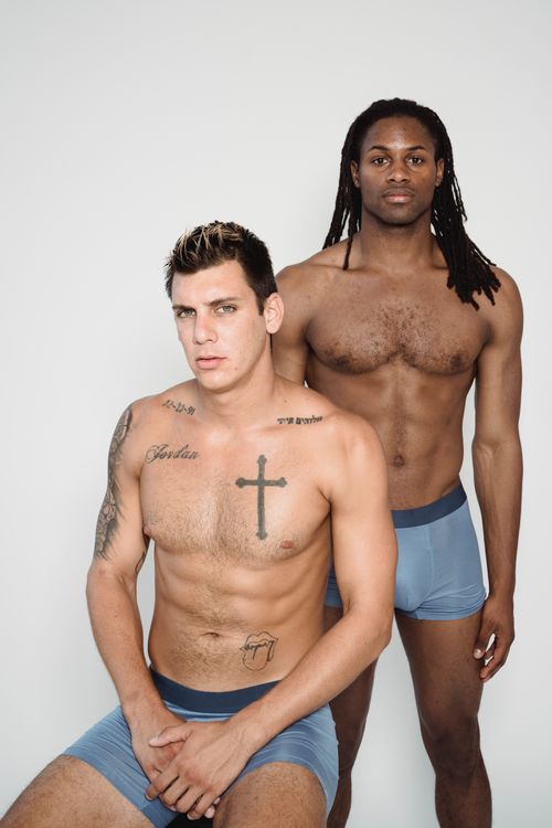 Free Two fit men pose shirtless in a studio, showcasing tattoos and toned physique. Stock Photo