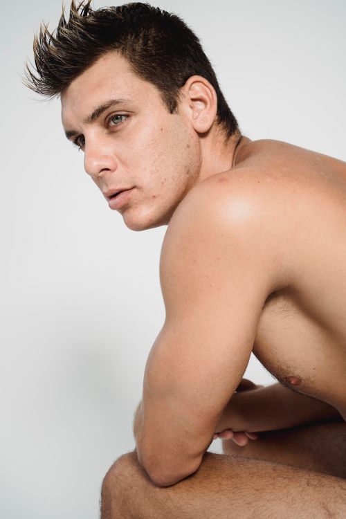 Free Shirtless male model posing in a studio setting, showcasing a fit physique. Stock Photo