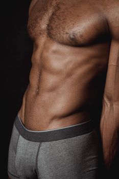 Close-up of a shirtless male torso showcasing muscles and strength for fitness and body care themes.