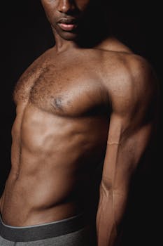 Close-up of an athletic man's muscular torso showing defined muscles in dramatic lighting.