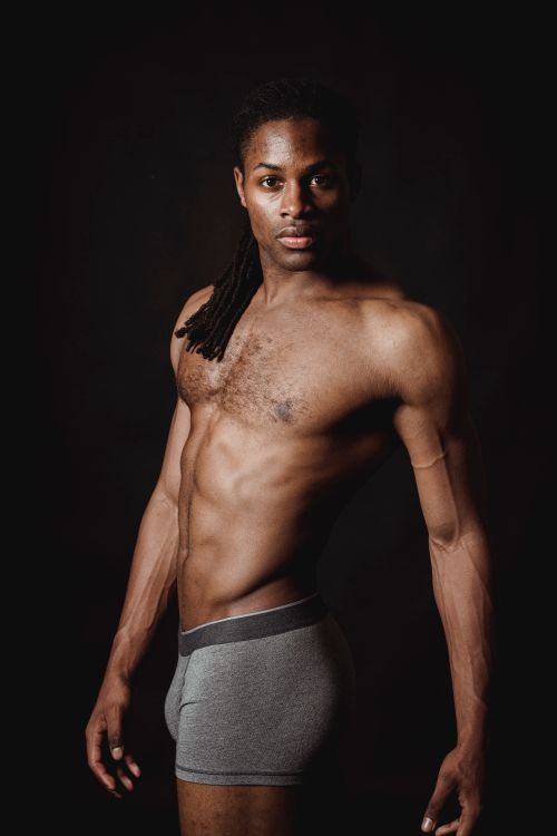 Free Muscular African American man posing shirtless in a studio with a dark background. Stock Photo