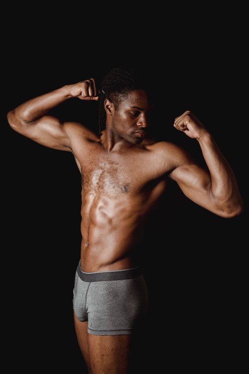 Free Fit African American man flexing muscles in a studio shoot, displaying strength and fitness. Stock Photo