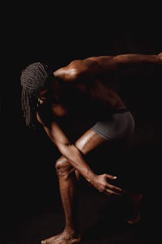 Shirtless muscular man showcasing a powerful athletic pose in a studio setting.