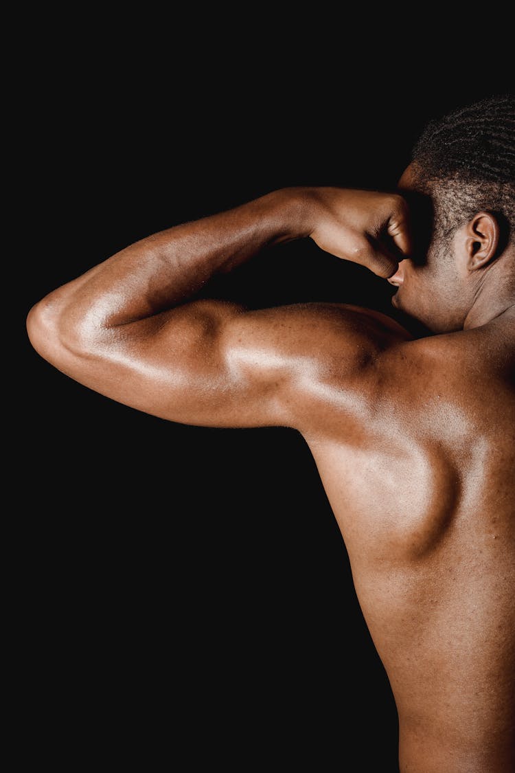 Studio Shoot Of A Mans Muscular Back And Arm Against Black Background