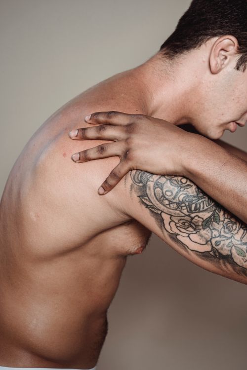 Free Close-up of a muscular man with tattoos posing shirtless, showcasing arm and shoulder details. Stock Photo
