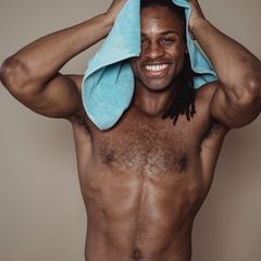 A smiling man drying his hair with a towel after a shower