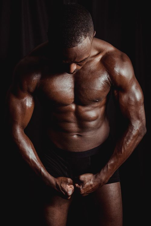 Free Muscular man flexing in a studio, showcasing defined abs and strength. Stock Photo