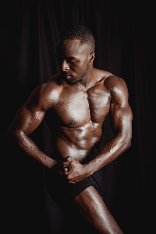Buff black man flexing his muscles, staring at you. accurate on