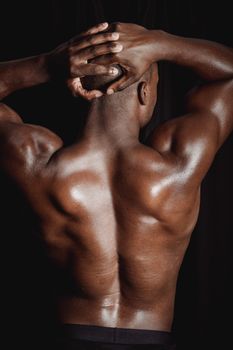 Shot of a shirtless muscular man flexing his back muscles, displaying strength and fitness.