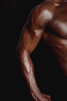 Close-up of a masculine arm highlighting muscle definition under low light for a dramatic effect.