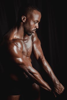 Artistic low-light studio portrait of a muscular African male with a focus on physique.