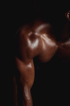 Close-up of a well-defined muscular arm, highlighting fitness and strength in low light.