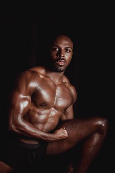 Shot of a muscular man flexing his physique in a dark studio setting.