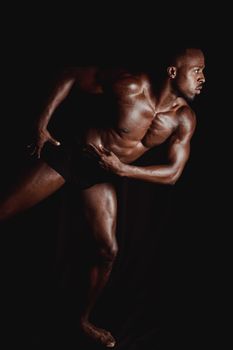 A shirtless, muscular man in a dramatic pose against a black background.