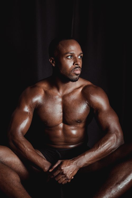 Free Athletic, shirtless man posing confidently in a low-light studio, highlighting muscular physique. Stock Photo