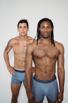 Studio shot of two shirtless men in blue underwear showcasing fitness and style.