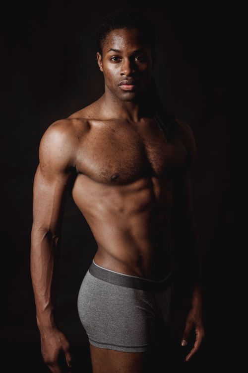 Free A muscular man posing shirtless against a dark background, showcasing fitness and strength. Stock Photo
