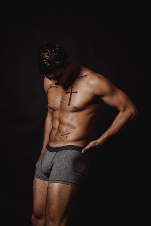 Free Portrait of a fit, tattooed man posing shirtless in a studio setting, showcasing strength and physique. Stock Photo