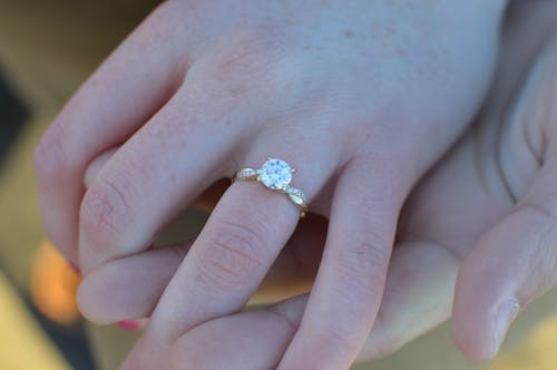 Close-Up Photograph of a Person's Hand Wearing a Ring with a Diamond