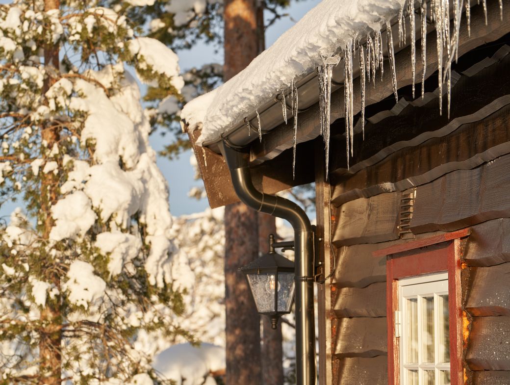 Cozy wooden cabin with icicles on the roof, set in a snowy forest
