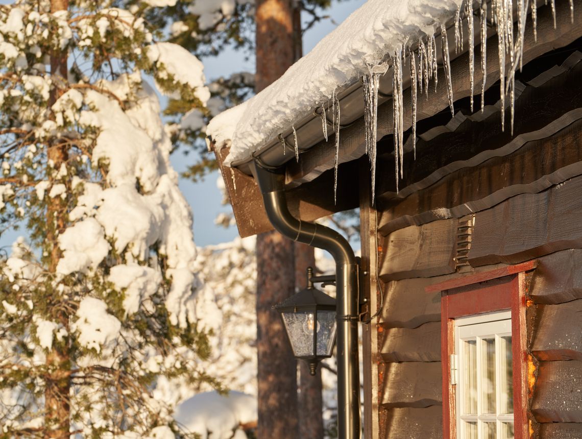 Cozy wooden cabin with icicles on the roof, set in a snowy forest