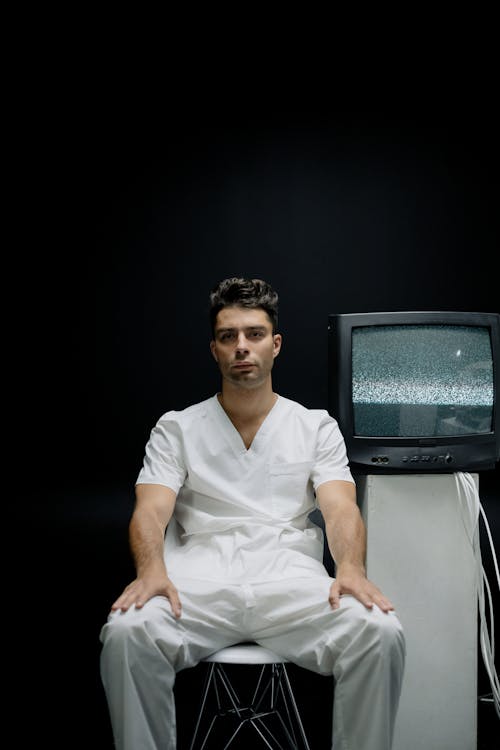 Free Man in White Scrub Suit Sitting on a Chair Stock Photo