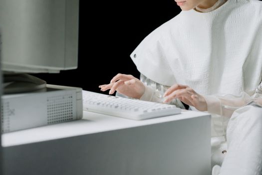 A woman in a white outfit typing on a white keyboard in a modern setting.