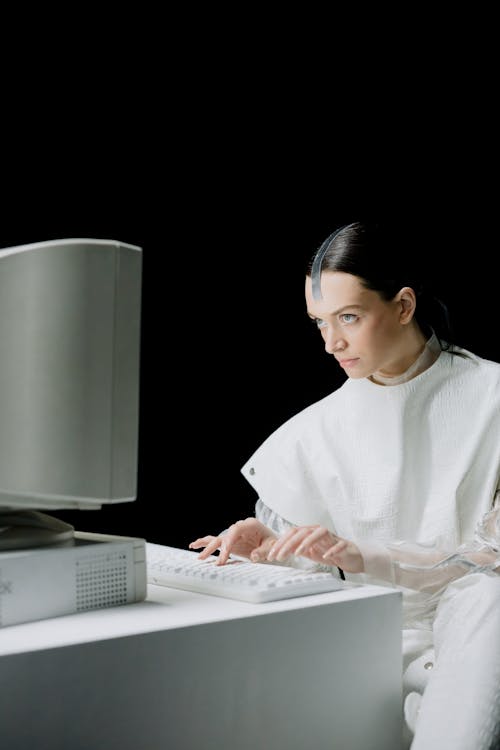 Woman in White Long Sleeve Shirt Using Computer