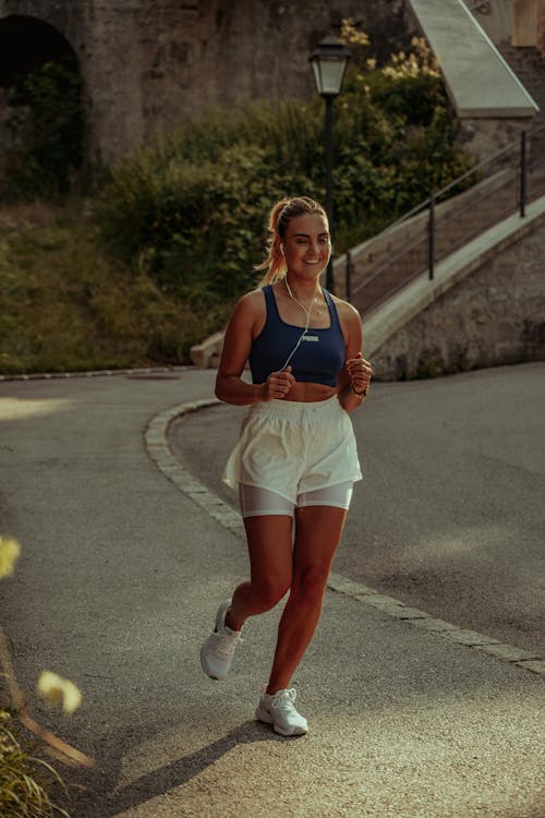 Woman in Blue Tank Top Running on Road With Earphones