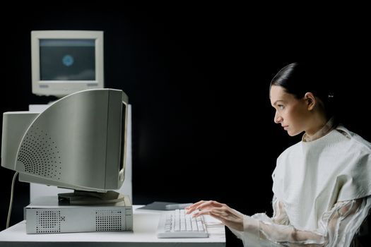 A woman typing on a retro CRT computer in a modern laboratory setting.