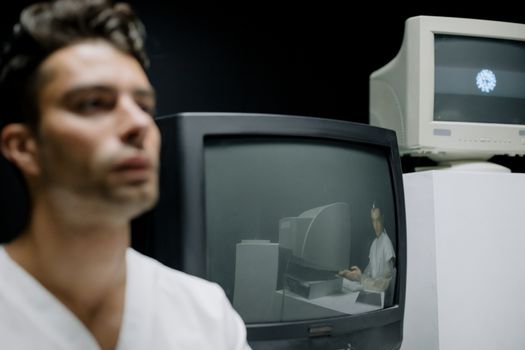 A thoughtful man is seen alongside vintage monitors, creating a reflective and nostalgic setting.