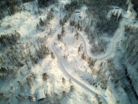 Stunning aerial shot of a snowy winding road through a forest in Krødsherad, Norway.