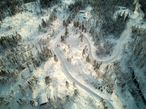 Free Stunning aerial shot of a snowy winding road through a forest in Krødsherad, Norway. Stock Photo