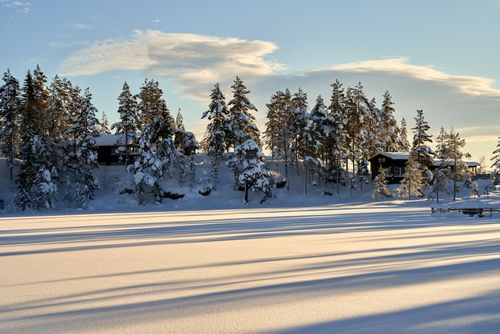 Free Peaceful winter scene featuring snow-laden trees and cabins under a clear blue sky. Stock Photo